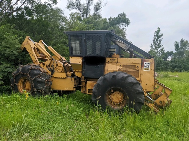 a yellow colored used grapple skidder in the field