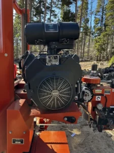 Buyer inspecting the engine and hydraulic system of a used portable sawmill before purchase